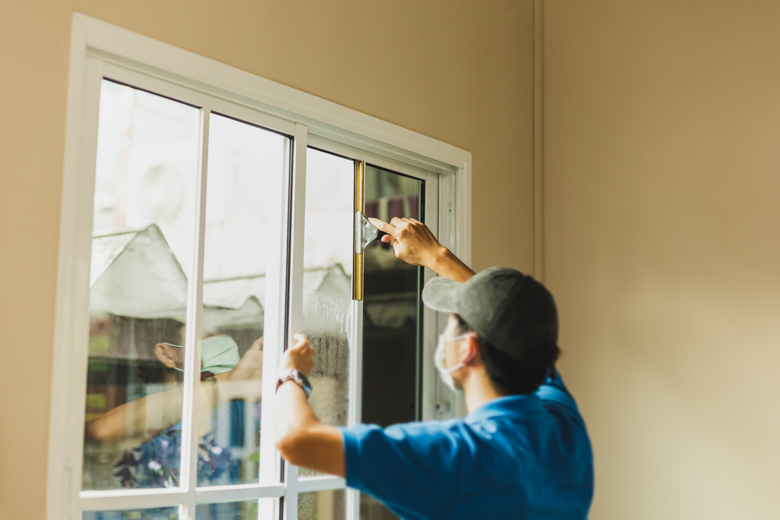 Worker use scraper cleaning window before installing tinting win